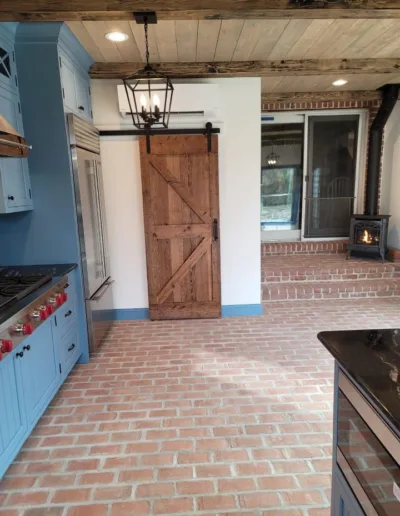 A kitchen with blue cabinets and a brick floor.