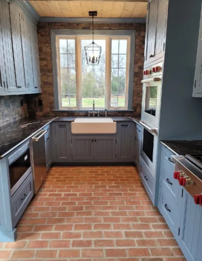 A kitchen with blue cabinets and a brick floor.