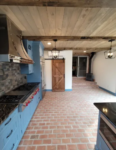 A kitchen with blue cabinets and a brick floor.