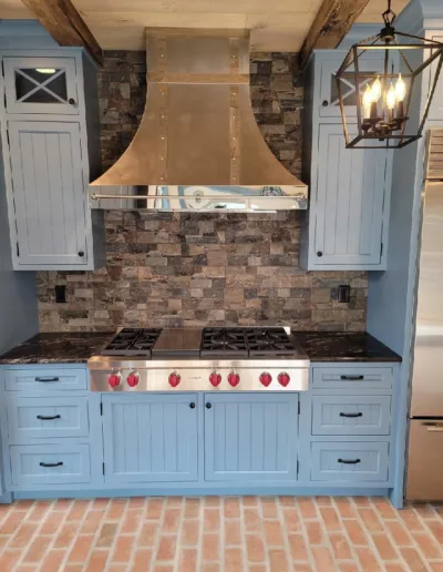 A kitchen with blue cabinets and a brick floor.