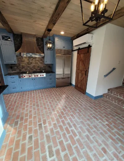 A kitchen with blue cabinets and a brick floor.