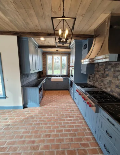 A kitchen with blue cabinets and a brick floor.
