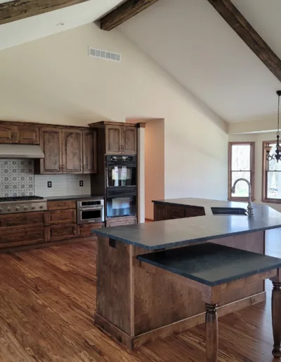 A kitchen with wooden beams and wood floors.