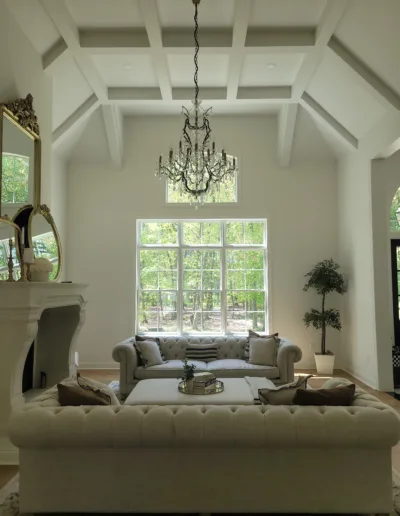 A living room with large windows and a chandelier.