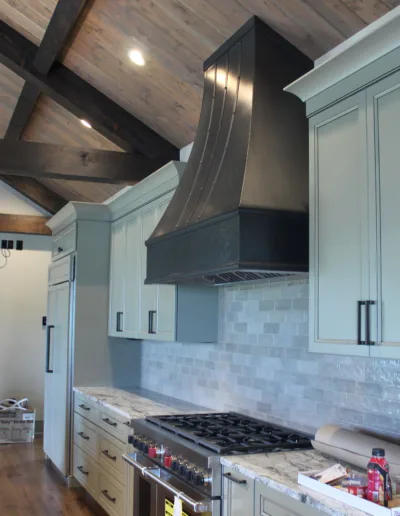A kitchen with wood beams and a stove.