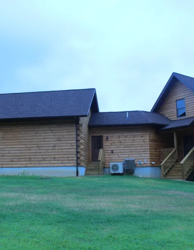A large log house on a grassy field.