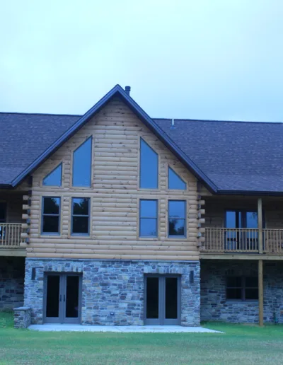 A large log home on a grassy field.