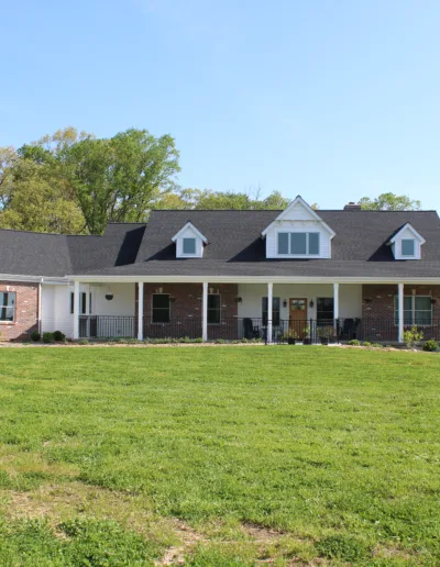 A brick home in the middle of a grassy field.