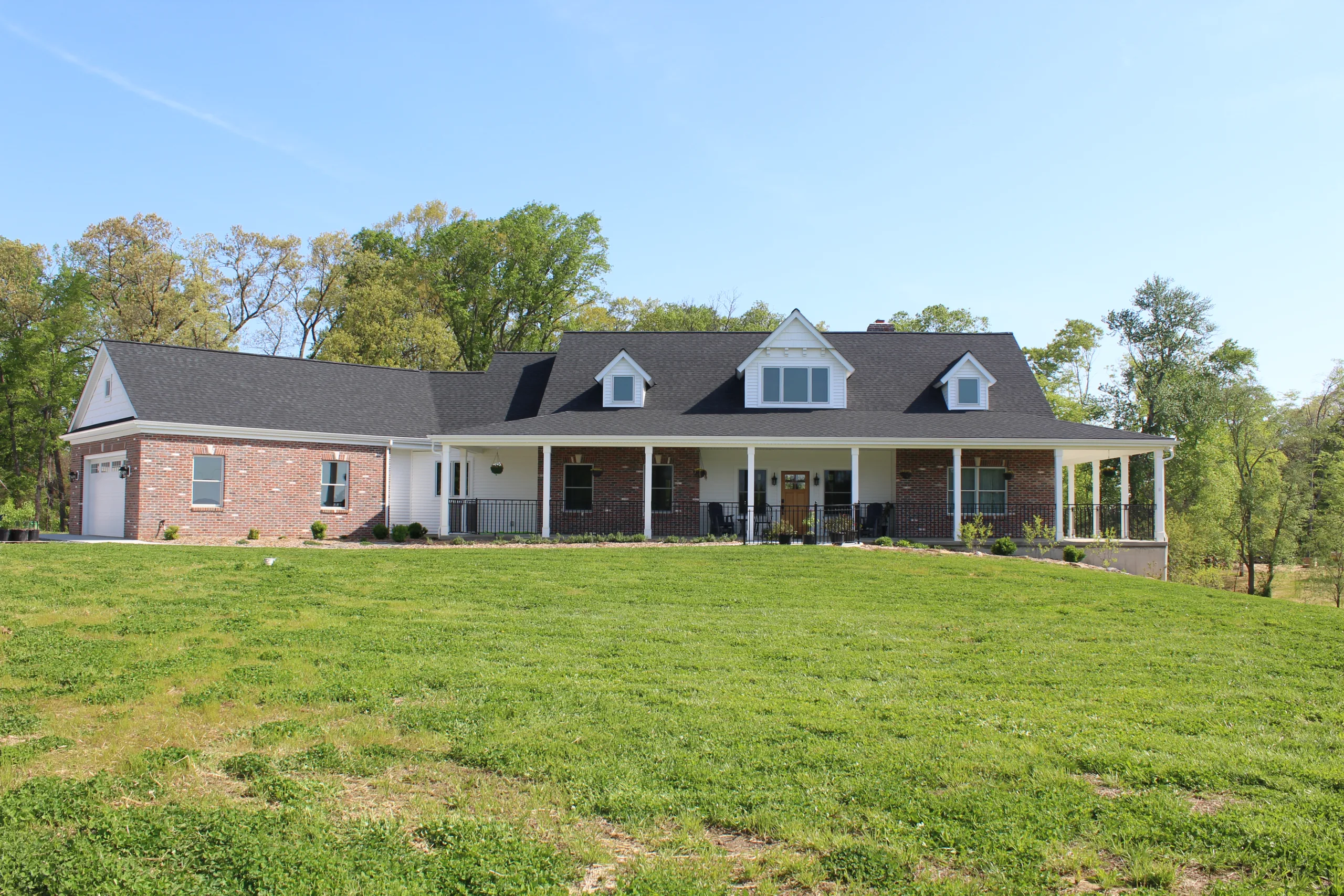 A brick home in the middle of a grassy field.
