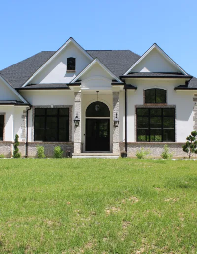 A white and black house in the middle of a grassy field.
