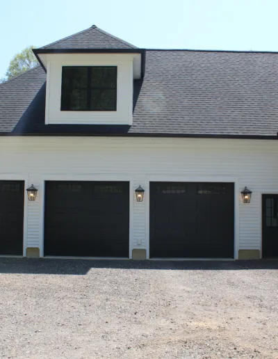 A white house with black garage doors.